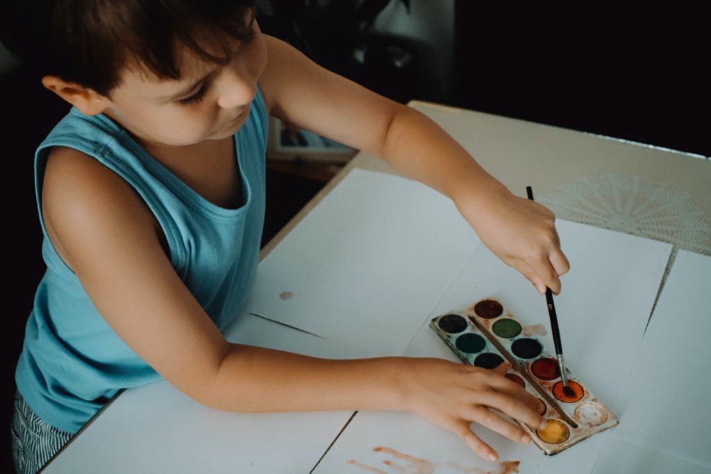 niño pintando con acuarelas como parte de RSE de dueños Corporativo Kosmos