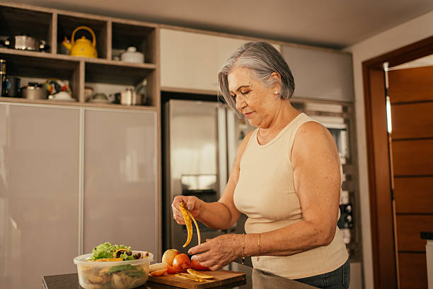 Mujer mayor prepara comida saludable en una cocina. Corporativo Kosmos impulsa la alimentación saludable de los adultos mayores.
